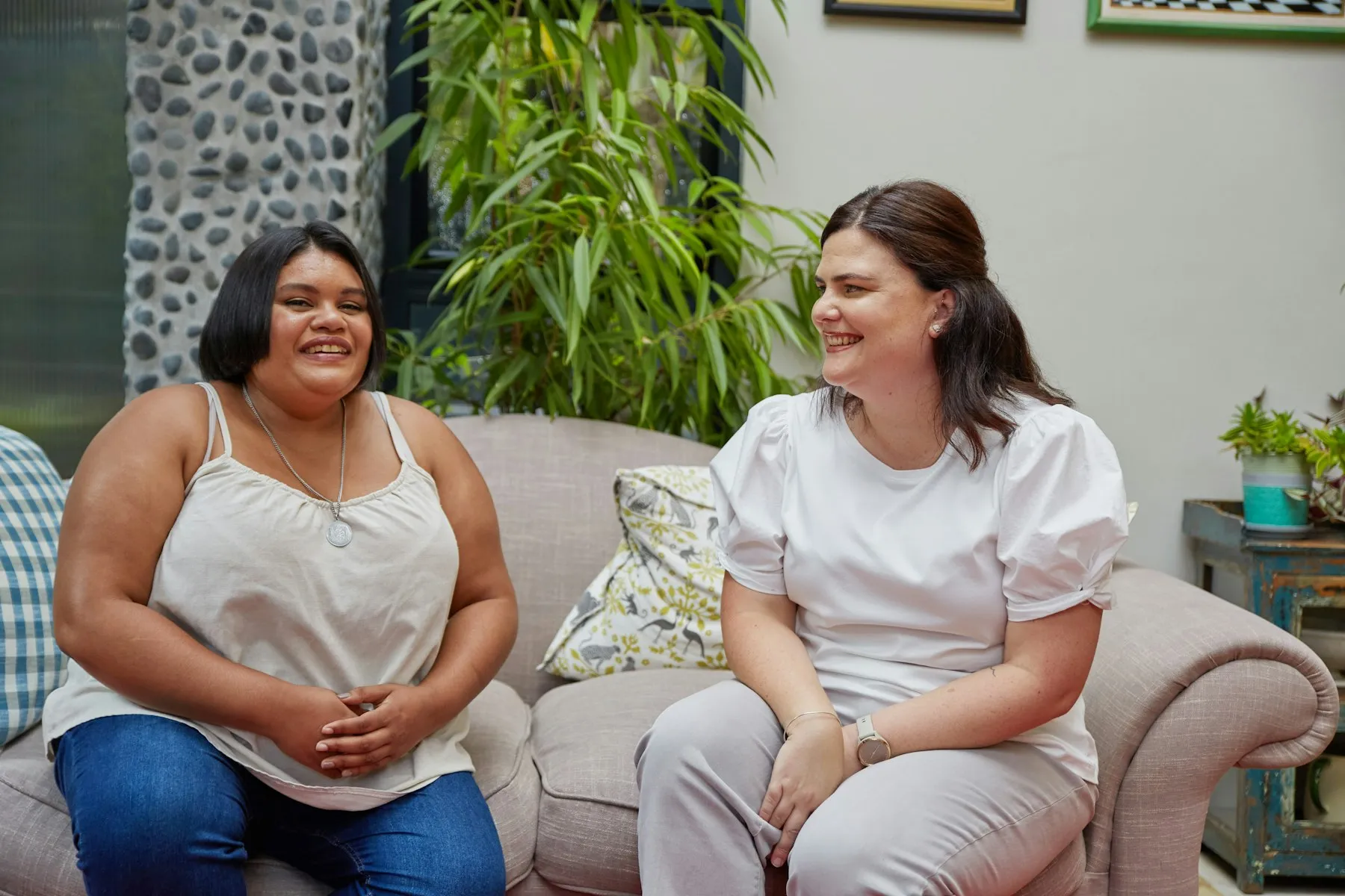 Dos mujeres conversando y riendo en un sofá