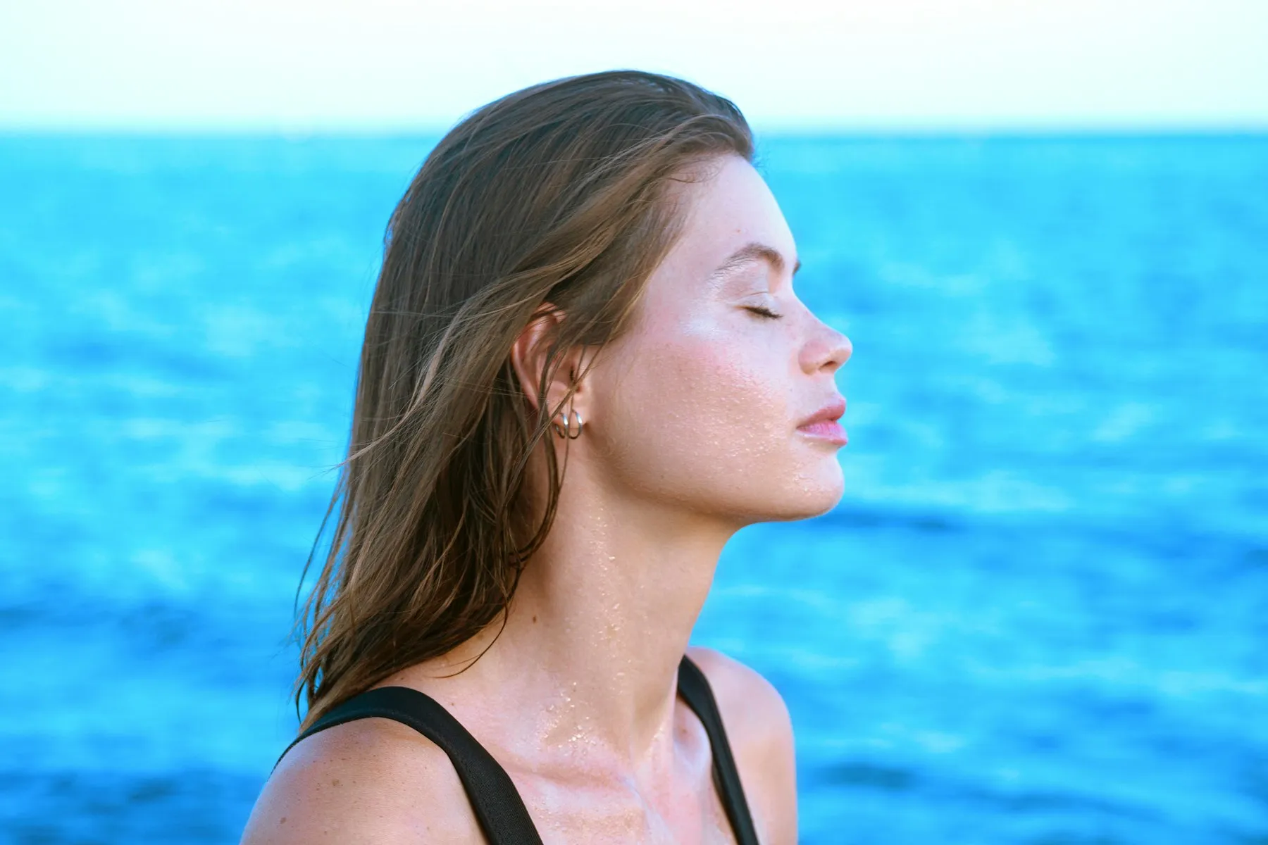 Mujer respirando con los ojos cerrados frente al mar